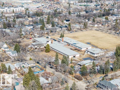 Aerial view of the surrounding neighborhood, featuring residential properties, a large open field, and several buildings with flat roofs - 8736 76 Avenue, Edmonton, AB - Outdoor With View