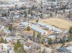 Aerial view of the surrounding neighborhood, featuring residential properties, a large open field, and several buildings with flat roofs - 