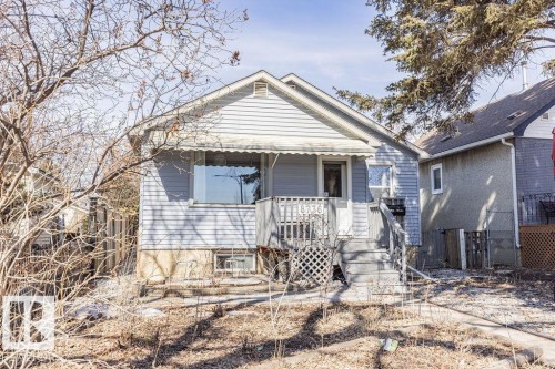 The property features light blue siding, a covered porch with wooden railings, and a front awning - 8736 76 Avenue, Edmonton, AB - Outdoor