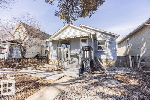 This property features a front porch with an awning, a concrete walkway, and a gravel front yard - 8736 76 Avenue, Edmonton, AB - Outdoor