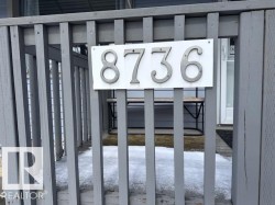 The property features a porch with gray wooden railings and a clearly visible house number display - 