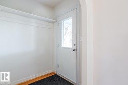 Entryway featuring a white door with a window, hardwood flooring, and a storage shelf - 