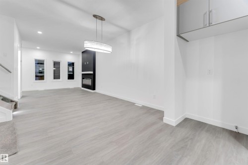 Spacious interior featuring light-toned flooring, recessed lighting, and a modern chandelier - 444 Crystal Creek Link, Leduc, AB - Indoor Photo Showing Other Room