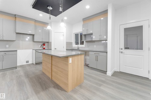 The kitchen features light grey cabinetry, a central island with a light-colored countertop, and recessed lighting - 444 Crystal Creek Link, Leduc, AB - Indoor Photo Showing Kitchen