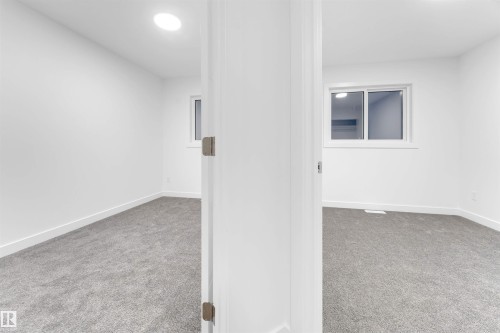 The property features a room with light grey carpet flooring, white walls, and a window providing natural light - 444 Crystal Creek Link, Leduc, AB - Indoor Photo Showing Other Room