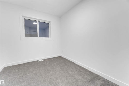 This room features a window providing natural light, white walls, and grey carpeting - 444 Crystal Creek Link, Leduc, AB - Indoor Photo Showing Other Room