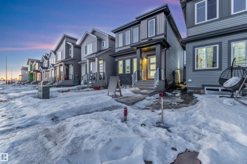 The property features a contemporary design with grey siding and contrasting white trim around the windows - 444 Crystal Creek Link, Leduc, AB - Outdoor With Facade