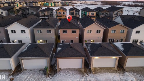This property features a two-story design with a light-colored exterior and a dark shingled roof - 444 Crystal Creek Link, Leduc, AB - Outdoor