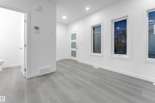 This open-concept area features light gray flooring, white walls, and recessed lighting - 444 Crystal Creek Link, Leduc, AB - Indoor Photo Showing Other Room