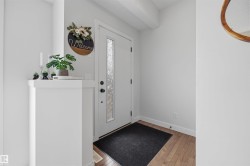 Entryway featuring a white door with a textured glass insert, hardwood flooring, and light-colored walls - 