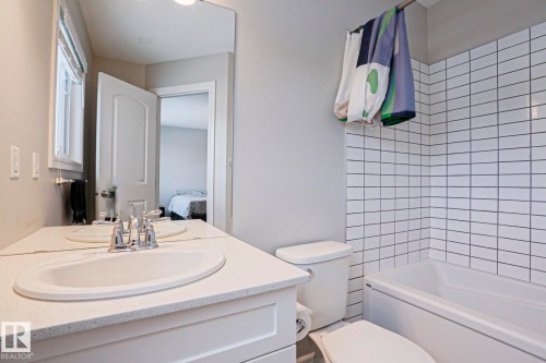 Bathroom featuring a vanity with an integrated sink, a mirror, and a bathtub with white subway tile surround - 1424 Mcconachie Boulevard, Edmonton, AB - Indoor Photo Showing Bathroom