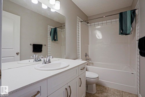 Bathroom with a white vanity featuring an integrated sink, a large mirror, and a combination bathtub and shower with white subway tile surround - 1424 Mcconachie Boulevard, Edmonton, AB - Indoor Photo Showing Bathroom