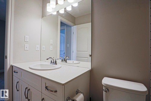 The bathroom features a vanity with a white countertop and an integrated sink, polished chrome faucet, and a large mirror - 1424 Mcconachie Boulevard, Edmonton, AB - Indoor Photo Showing Bathroom