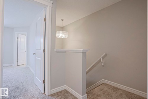 The property features neutral-toned walls, light grey carpet, and white trim throughout - 1424 Mcconachie Boulevard, Edmonton, AB - Indoor Photo Showing Other Room