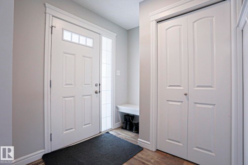 Inviting entryway featuring a white paneled door with an overhead transom window and a full-length sidelight, wood-look flooring, and a built-in bench - 1424 Mcconachie Boulevard, Edmonton, AB - Indoor Photo Showing Other Room