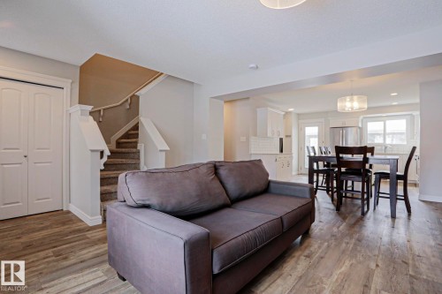 The property features an open-concept living area with wood-look flooring and a staircase with carpeted treads - 1424 Mcconachie Boulevard, Edmonton, AB - Indoor Photo Showing Living Room
