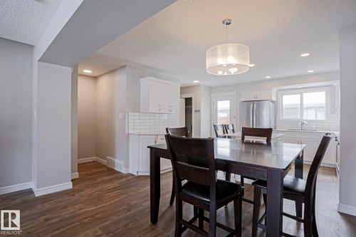 Open concept kitchen and dining area featuring hardwood flooring, white cabinetry, a subway tile backsplash, and a stainless steel refrigerator - 1424 Mcconachie Boulevard, Edmonton, AB - Indoor Photo Showing Dining Room