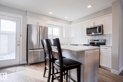 The kitchen features white cabinetry, stainless steel appliances, and a white subway tile backsplash - 1424 Mcconachie Boulevard, Edmonton, AB - Indoor Photo Showing Kitchen With Stainless Steel Kitchen