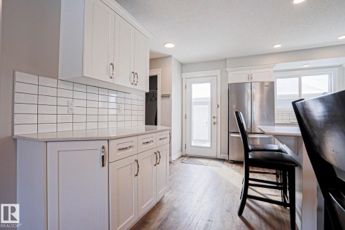 The property features a kitchen with white cabinetry, a tiled backsplash, and recessed lighting - 1424 Mcconachie Boulevard, Edmonton, AB - Indoor Photo Showing Kitchen