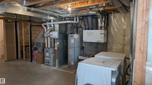 The property includes a utility area with exposed ceiling joists, ductwork, and a water heater, alongside a washer and dryer - 1424 Mcconachie Boulevard, Edmonton, AB - Indoor Photo Showing Basement