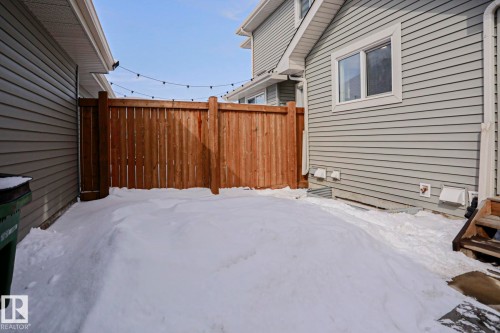 The property features a fenced yard with a wooden fence and string lights, providing a private outdoor space - 1424 Mcconachie Boulevard, Edmonton, AB - Outdoor With Exterior