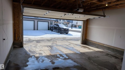 The property includes an attached garage with an automatic overhead door, concrete flooring, and exposed ceiling beams - 1424 Mcconachie Boulevard, Edmonton, AB - Indoor Photo Showing Garage