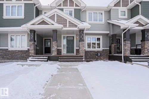 The property features a front entrance with a dark gray door, covered porch, and stone-accented pillars - 1424 Mcconachie Boulevard, Edmonton, AB - Outdoor With Facade