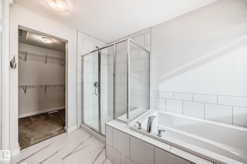 Spacious bathroom featuring a glass-enclosed shower, a built-in bathtub, and white tiled walls - 2935 Chokecherry Common, Edmonton, AB - Indoor Photo Showing Bathroom