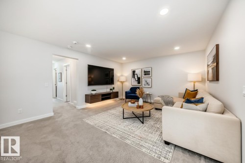 The property features a living area with plush carpeting, recessed lighting, and a neutral color palette - 2935 Chokecherry Common, Edmonton, AB - Indoor Photo Showing Living Room