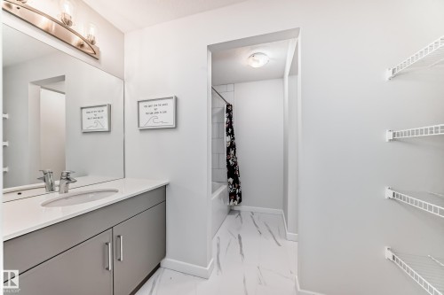 Well-appointed bathroom featuring a vanity with a white countertop, an undermount sink, and a large mirror with overhead lighting - 2935 Chokecherry Common, Edmonton, AB - Indoor