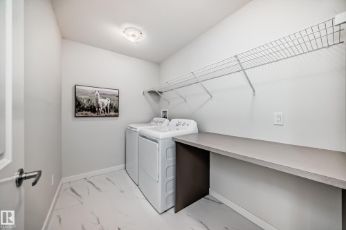 Utility room featuring light-colored walls, patterned flooring, and overhead shelving - 2935 Chokecherry Common, Edmonton, AB - Indoor Photo Showing Laundry Room
