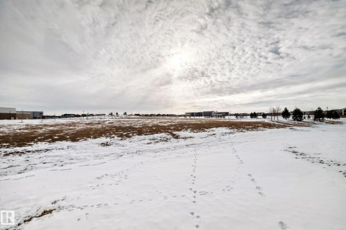 Expansive undeveloped land area featuring a mix of snow-covered ground and visible patches of brown vegetation - 2935 Chokecherry Common, Edmonton, AB - Outdoor With View