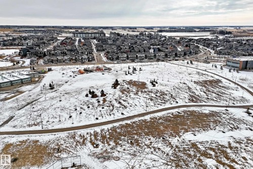 Aerial view showcasing a residential area featuring numerous detached properties, a public park with walking paths, and additional buildings in the background - 2935 Chokecherry Common, Edmonton, AB - Outdoor With View