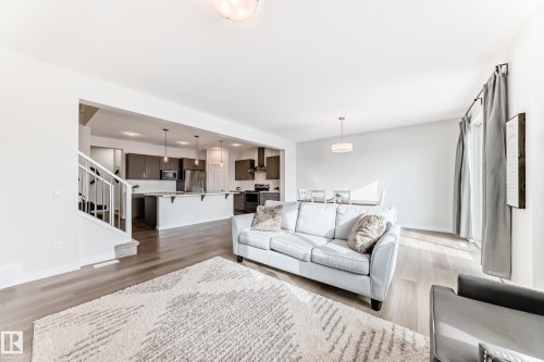 The property features an open living area with light wood flooring and a staircase with white railings - 2935 Chokecherry Common, Edmonton, AB - Indoor Photo Showing Living Room