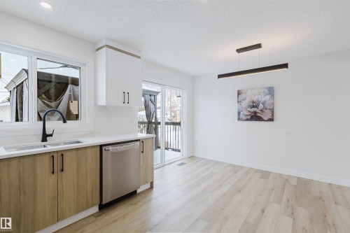 The kitchen features a stainless steel dishwasher, a single basin sink with a black matte faucet, and light wood cabinetry with black hardware - 11528 42 Avenue, Edmonton, AB - Indoor Photo Showing Kitchen With Double Sink