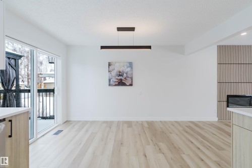 The property features light-toned flooring, a linear ceiling light fixture, and a sliding glass door providing access to an exterior area with a black railing - 11528 42 Avenue, Edmonton, AB - Indoor