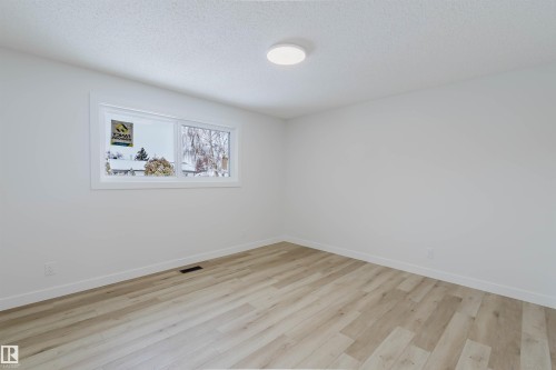 This room features light-toned wood-look flooring, white walls, and a window with white trim - 11528 42 Avenue, Edmonton, AB - Indoor Photo Showing Other Room