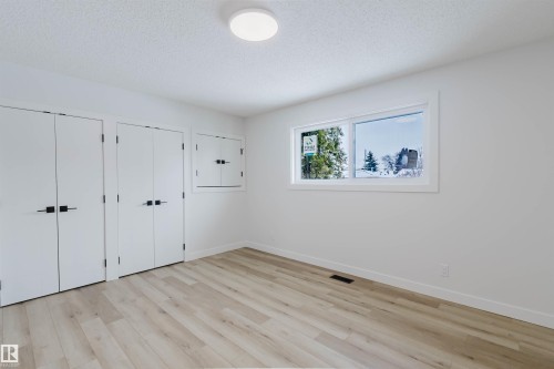 This room features light-toned hardwood flooring, white walls, and a window providing natural light - 11528 42 Avenue, Edmonton, AB - Indoor Photo Showing Other Room