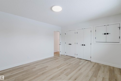 This bright room features light-colored plank flooring, white walls, and a circular ceiling light fixture - 11528 42 Avenue, Edmonton, AB - Indoor Photo Showing Other Room