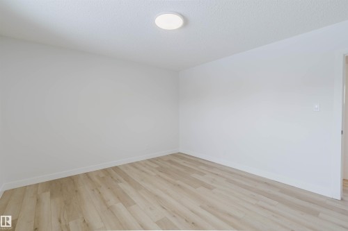 This room features light-toned wood-style flooring and bright white walls, complemented by a recessed light fixture on the ceiling - 11528 42 Avenue, Edmonton, AB - Indoor Photo Showing Other Room
