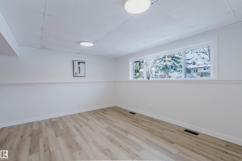 This room features light wood-style flooring, white walls, and a large window - 11528 42 Avenue, Edmonton, AB - Indoor Photo Showing Other Room