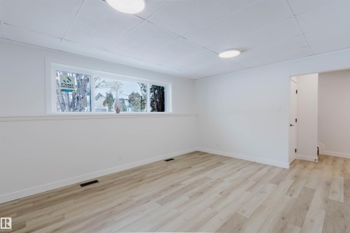 This bright room features light-toned flooring, white walls, and a large window providing natural light - 11528 42 Avenue, Edmonton, AB - Indoor Photo Showing Other Room