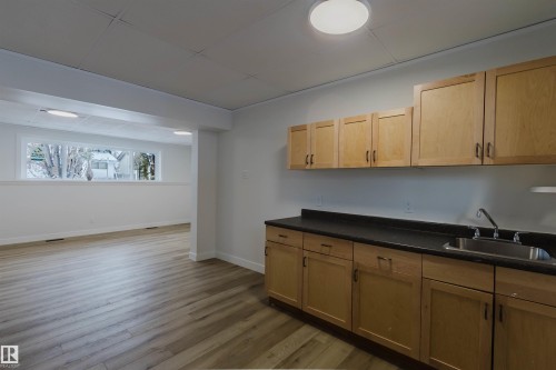 The property offers a functional wet bar area with wooden cabinetry, a dark countertop, and a stainless steel sink - 11528 42 Avenue, Edmonton, AB - Indoor Photo Showing Kitchen