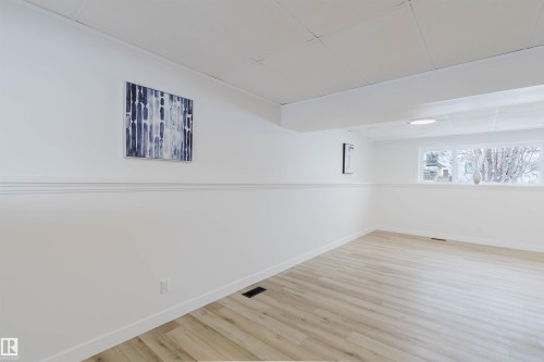 This bright room features light-toned flooring, white walls with decorative trim, and a window providing natural light - 11528 42 Avenue, Edmonton, AB - Indoor Photo Showing Other Room