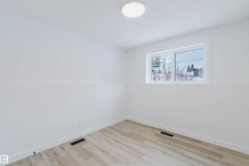 This room features light-colored laminate flooring, white walls, and a window providing natural light - 11528 42 Avenue, Edmonton, AB - Indoor Photo Showing Other Room