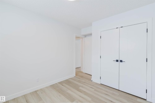 This room features light-toned wood flooring, crisp white walls, and a pair of white doors with black hardware - 11528 42 Avenue, Edmonton, AB - Indoor Photo Showing Other Room