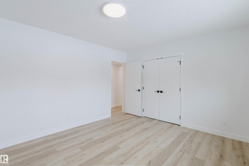 This room features light-toned wood-style flooring, white walls, and a modern ceiling light fixture - 11528 42 Avenue, Edmonton, AB - Indoor Photo Showing Other Room