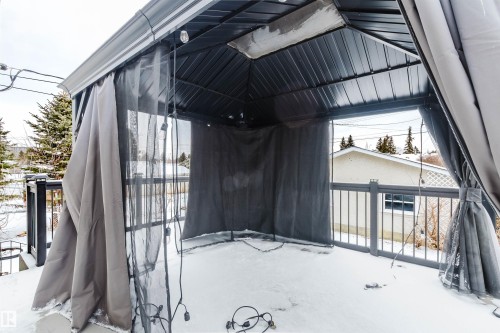 The property includes an outdoor covered patio area with privacy screens, a metal railing, and string lights - 11528 42 Avenue, Edmonton, AB - Outdoor With Exterior