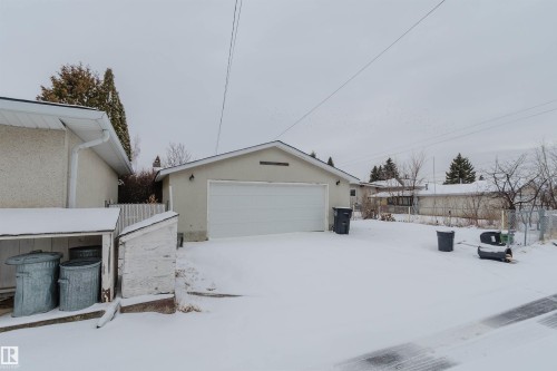 The property features an exterior garage with a white garage door, and a light-colored stucco finish - 11528 42 Avenue, Edmonton, AB - Outdoor With Exterior