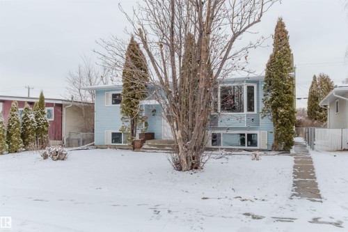 The property features light blue siding, a front yard with mature trees, and a concrete walkway leading to the entrance - 11528 42 Avenue, Edmonton, AB - Outdoor